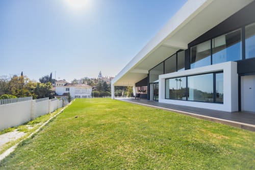 Terraza de lujo moderna en BH Marbella con jardín impecable, ventanales de suelo a techo y vistas al paisaje urbano de Marbella