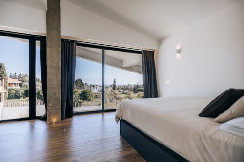 Amplio dormitorio moderno en BH Marbella con vistas panorámicas, suelos de madera y ventanales del piso al techo