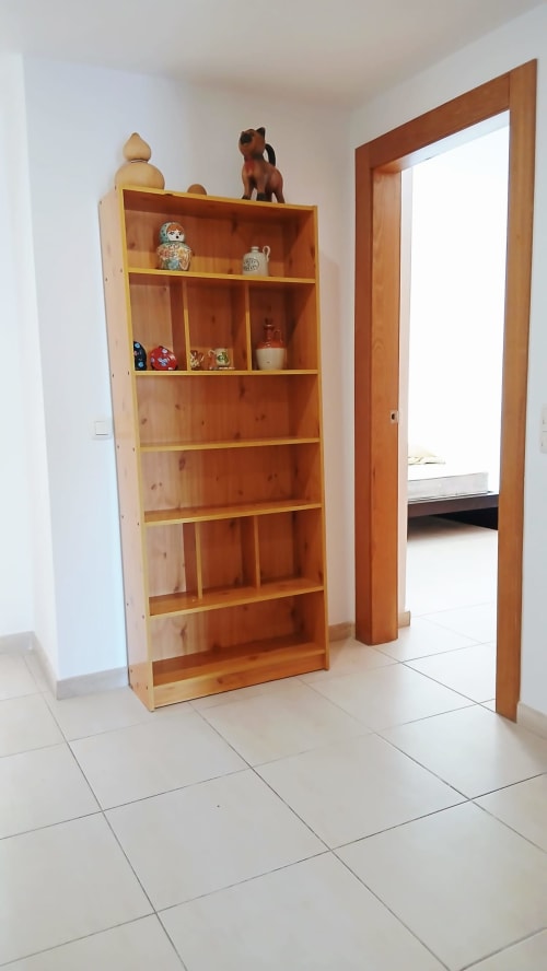 Unidade de prateleiras em madeira no corredor do apartamento Sweet Home, Portimão, exibindo itens decorativos e colecionáveis