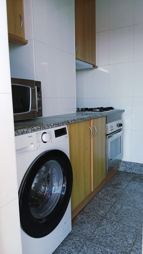 Cozinha moderna com máquina de lavar, fogão a gás e micro-ondas no apartamento Sweet Home, Portimão