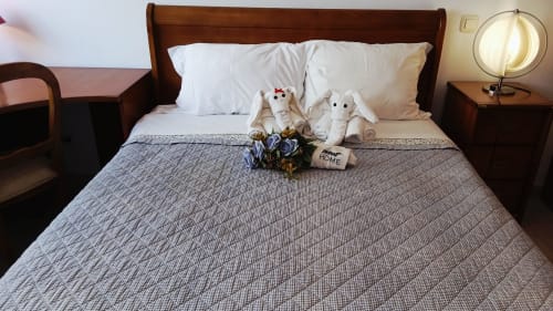 Quarto aconchegante em Sweet Home Portimão com dois bichinhos de pelúcia na cama, travesseiros brancos, manta azul e móveis de madeira