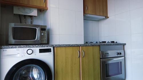 Cozinha do apartamento Sweet Home em Portimão com máquina de lavar LG, micro-ondas, fogão a gás e azulejos brancos