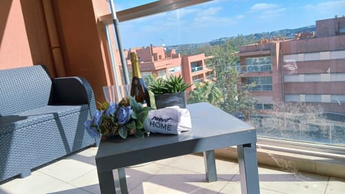 Varanda do apartamento Sweet Home em Portimão, com plantas em vasos com vista para edifícios de tijolos vermelhos e céu azul