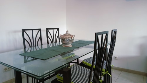 Área de refeições do apartamento Sweet Home em Portimão com mesa de vidro, cadeiras pretas e peça decorativa central