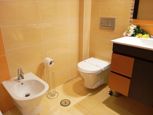Banheiro moderno com azulejos pêssego, acessórios brancos e gabinete escuro no apartamento Sweet Home em Portimão