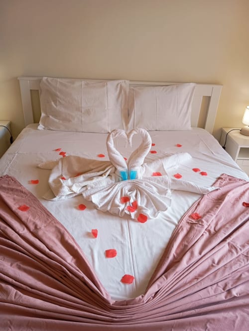 Quarto romântico em Sweet Home Borralha em Portimão com cisnes de toalha, pétalas de rosa e decoração de coração
