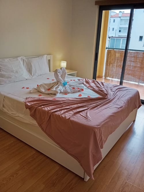 Quarto romântico com pétalas de rosa e cisne de toalha no apartamento Sweet Home Borralha em Portimão