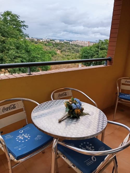 Área de estar na varanda do Sweet Home Borralha em Portimão com vista para a cidade, cadeiras Coca-Cola e paisagem de encostas.