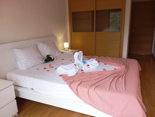 Quarto romântico no apartamento Sweet Home Borralha em Portimão decorado com pétalas de rosa e arranjo de toalhas