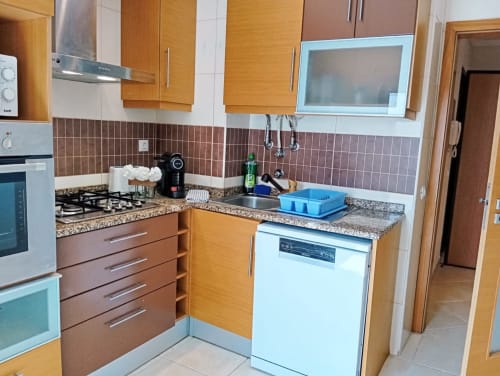 Cozinha moderna com armários de madeira, bancadas de granito e eletrodomésticos de aço inoxidável no apartamento Sweet Home Borralha