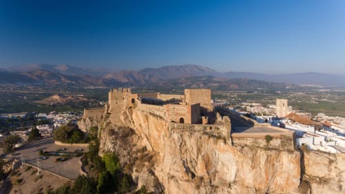 Fortaleza de Alcazaba encaramada en acantilado rocoso con vistas al valle de Salobreña, montañas y paisaje mediterráneo