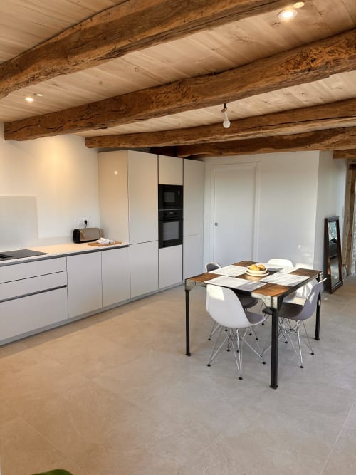 Cuisine moderne et coin repas de la villa Gite l'Harmonie du Causse avec poutres en bois apparentes, mobilier blanc et style rustique