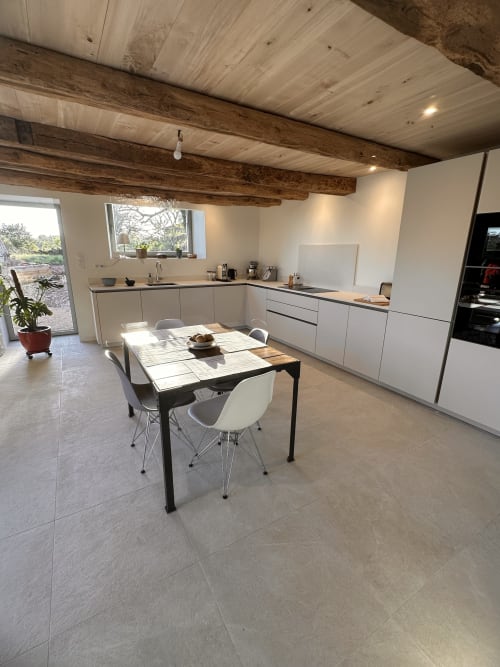 Cuisine-salle à manger moderne de la villa Gîte l'Harmonie du Causse avec armoires blanches, poutres en bois et table de salle à manger