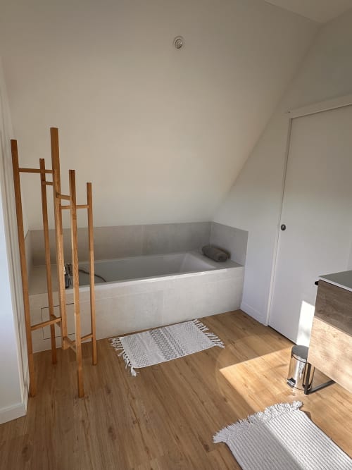 Salle de bains spacieuse de la villa Gite l'Harmonie du Causse avec baignoire, étagère échelle en bois et parquet