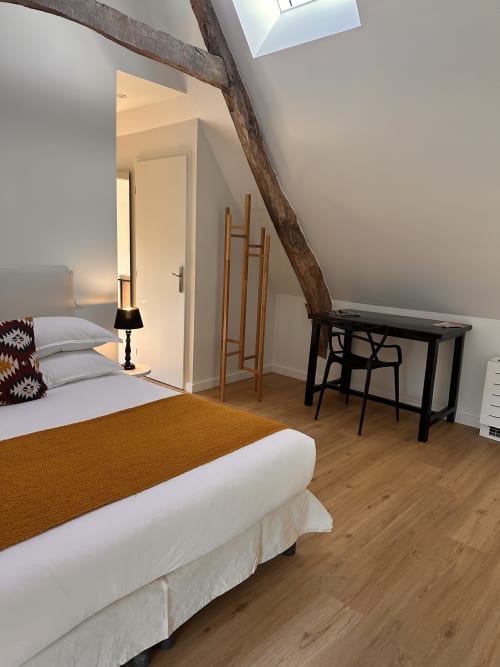 Chambre mansardée moderne au Gîte l'Harmonie du Causse avec poutres apparentes, lit, bureau et lucarne