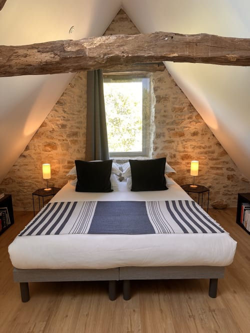 Chambre rustique sous les toits avec poutres apparentes, murs en pierre et fenêtre à la villa Gîte l'Harmonie du Causse