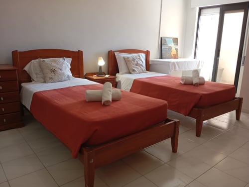 Dois leitos gêmeos com colchas vermelhas, estruturas em madeira e almofadas brancas no apartamento Sweet Home Vila Rosa, Portimão