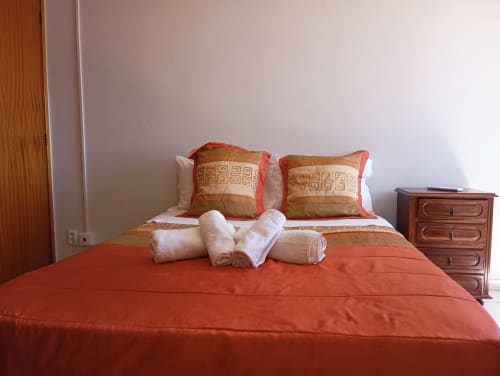 Quarto arrumado com esmero em Sweet Home Vila Rosa em Portimão com roupa de cama vermelha, almofadas decorativas e toalhas enroladas