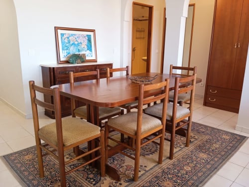 Sala de jantar do apartamento Sweet Home Vila Rosa em Portimão com mesa de madeira, cadeiras e aparador