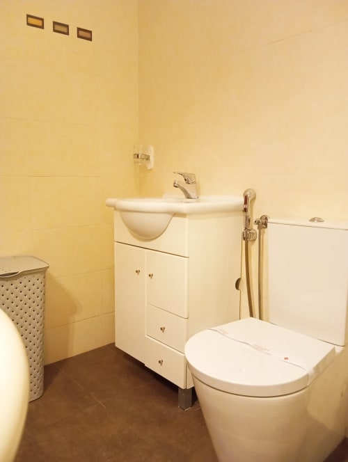 Casa de banho com azulejos amarelos, lavatório branco, sanita e bidé do apartamento Sweet Home Vila Rosa em Portimão