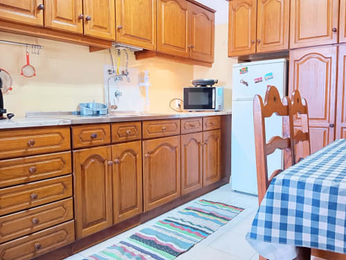 Cozinha de madeira com bancadas brancas, micro-ondas e frigorífico no apartamento Sweet Home Vila Rosa, Portimão