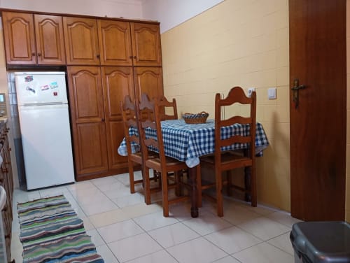 Cozinha-sala de jantar do apartamento Sweet Home Vila Rosa em Portimão, com móveis de madeira e toalha de mesa xadrez azul