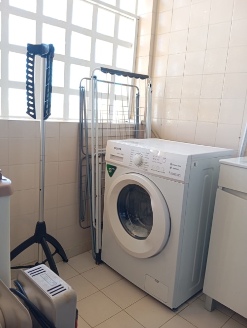 Lavanderia do apartamento Sweet Home Vila Rosa em Portimão com máquina de lavar e varal