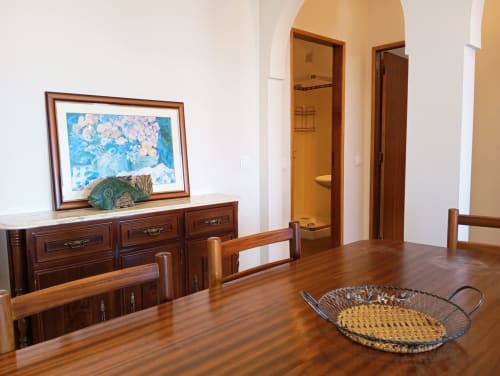 Mesa de jantar em madeira no apartamento Sweet Home Vila Rosa, Portimão, com cômoda, quadro floral emoldurado e portas