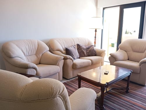Sala de estar do apartamento Sweet Home Vila Rosa em Portimão com sofás bege, mesa de madeira e vista para a cidade através de portas modernas