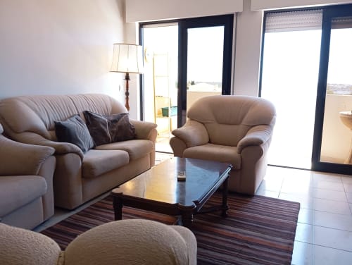 Sala de estar luminosa do apartamento Sweet Home Vila Rosa em Portimão, com assentos de couro bege e vistas para a cidade