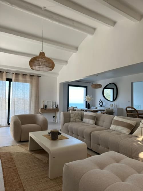 Salon de luxe moderne avec mobilier beige, poutres apparentes et vue sur la mer à La Conciergerie du Cap Corse, Centuri