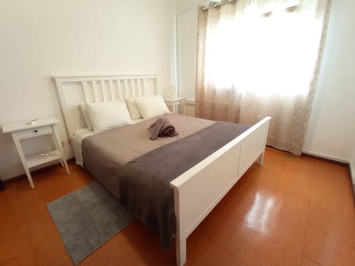 Quarto Sweet Home Inn em Portimão com móveis brancos, vista da cidade, piso em terracota e luz matinal