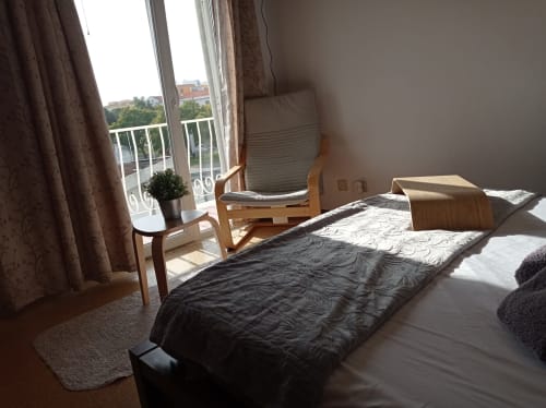 Bright hotel bedroom at Sweet Home in Portimão with city view balcony, wooden furniture, and natural sunlight