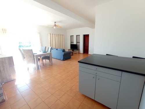 Apartamento luminoso no Sweet Home Inn Portimão com cozinha aberta, sala de jantar, sofá azul e vista para a cidade do terraço