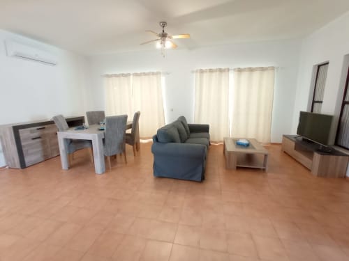 Ampla sala de estar do apartamento no Sweet Home Inn Terrace em Portimão com mesa de jantar, sofá azul e vista para a cidade