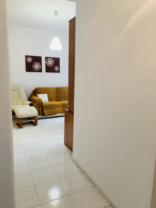 Entrada do corredor para quarto moderno no hotel Sweet Home em Portimão com sofá dourado, luminária de teto branca e arte decorativa na parede