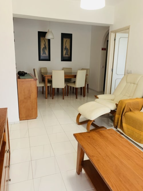 Sala de estar moderna no hotel Sweet Home em Portimão com mesa de jantar, poltrona creme e móveis de madeira