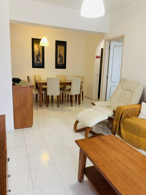 Sala de estar moderna do hotel Sweet Home em Portimão com assentos confortáveis, móveis de madeira e paredes com destaques amarelos