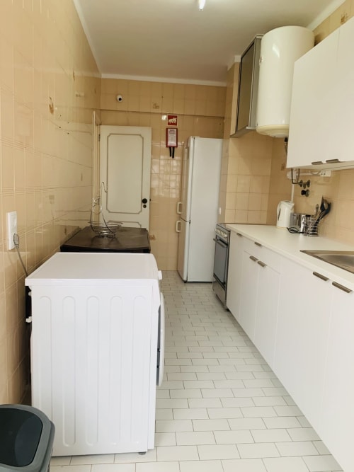Cozinha corredor no quarto do hotel Sweet Home em Portimão, com eletrodomésticos brancos e paredes com azulejos bege