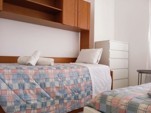 Quarto aconchegante no Sweet Home Portimão com roupa de cama xadrez, móveis de madeira e criados-mudos modernos