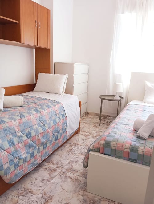 Quarto twin no hotel Sweet Home em Portimão com roupa de cama xadrez, cabeceira de madeira e vista para a cidade