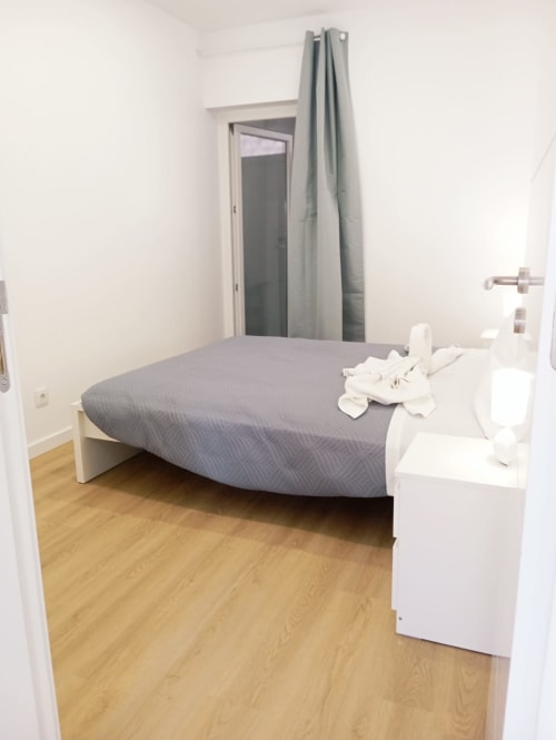 Quarto moderno no apartamento Sweet Home em Portimão com cama cinza, criado branco e piso de madeira