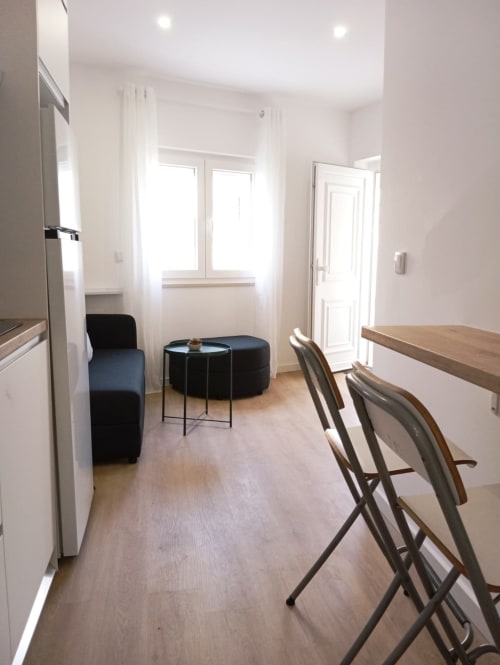 Apartamento moderno em Portimão com cozinha aberta, sala de jantar, assentos pretos e amplas janelas com vista para a cidade