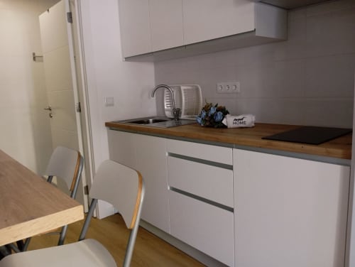 Kitchenette moderno do apartamento Sweet Home Sabino em Portimão, com armários brancos, bancada de madeira e área de refeições