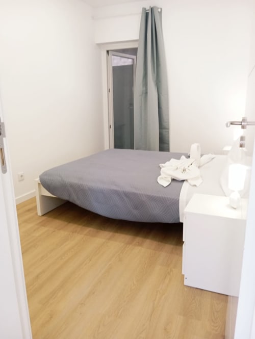 Quarto claro no apartamento Sweet Home Sabino, Portimão com roupa de cama cinzenta, móveis brancos e piso de madeira