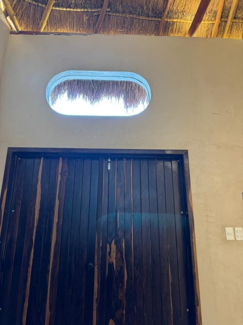 Puerta de madera oscura con ventana ovalada en la Habitación Sábalo de Ala Residencias, Chetumal, México