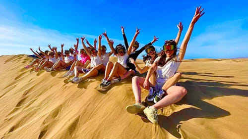 Groupe de voyageurs célébrant sur les dunes de sable du désert près du Riad Eucalyptus à El Ghazouane, Maroc