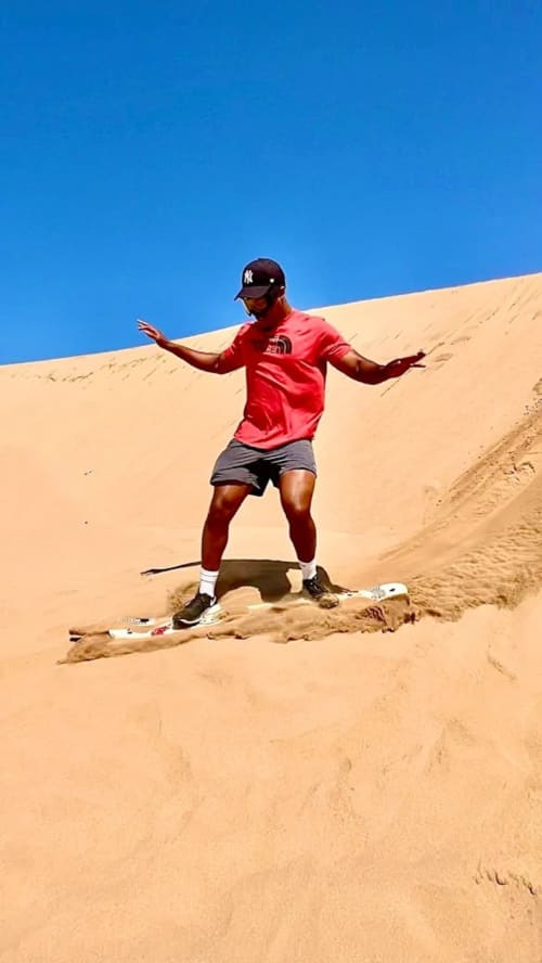 Homme en kitesurf sur les dunes de sable désertiques près du Riad Eucalyptus à El Ghazouane, Maroc