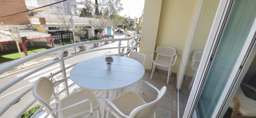 Balcón de Apartamentos Voramar en Cambrils con mesa redonda blanca, sillas blancas y vistas a la ciudad
