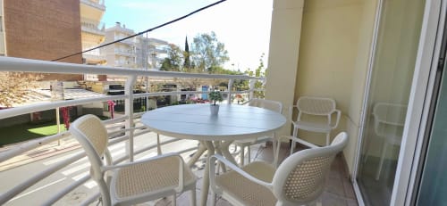 Amplio balcón en Apartaments Voramar, Cambrils, con mesa redonda, sillas blancas y vistas a la ciudad